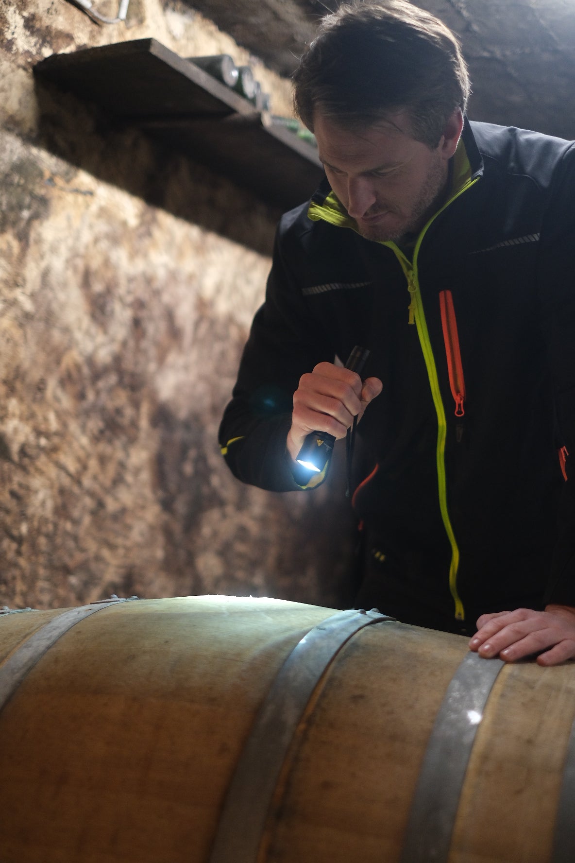 Corvin leuchtet mit einer Taschenlampe in ein Holzfass